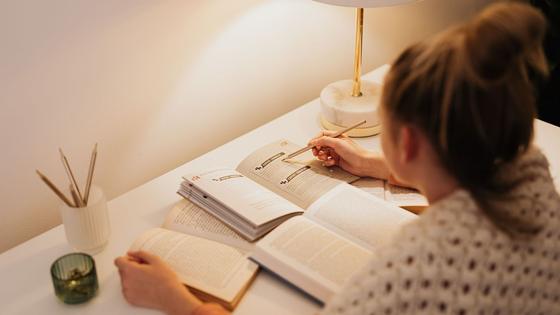 Réviser le soir, un livre et un carnet sous la lampe